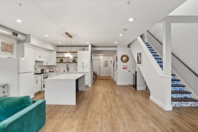 kitchen featuring sink, white appliances, white cabinetry, a center island, and decorative light fixtures