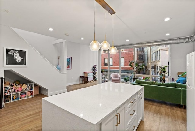 kitchen with white cabinetry, decorative light fixtures, light wood-type flooring, and a kitchen island