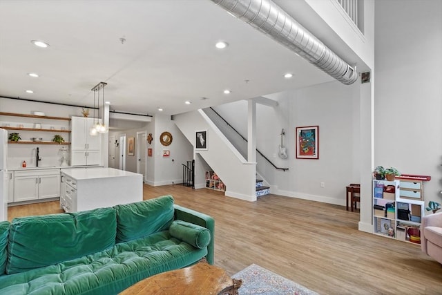 living room featuring a barn door, sink, and light hardwood / wood-style floors