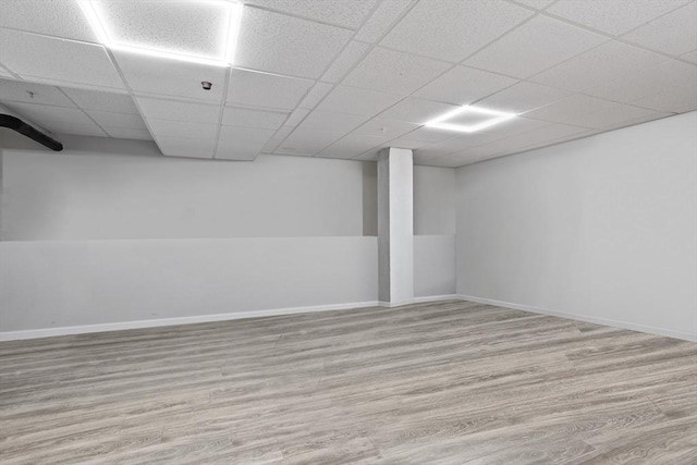 basement featuring a paneled ceiling and light wood-type flooring