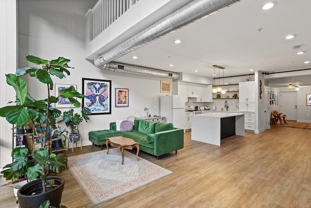 living room featuring ceiling fan, sink, and light hardwood / wood-style flooring