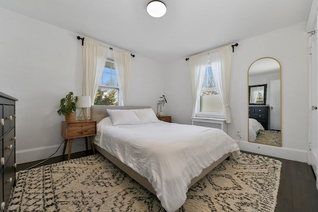 bedroom with radiator heating unit, multiple windows, and dark hardwood / wood-style flooring