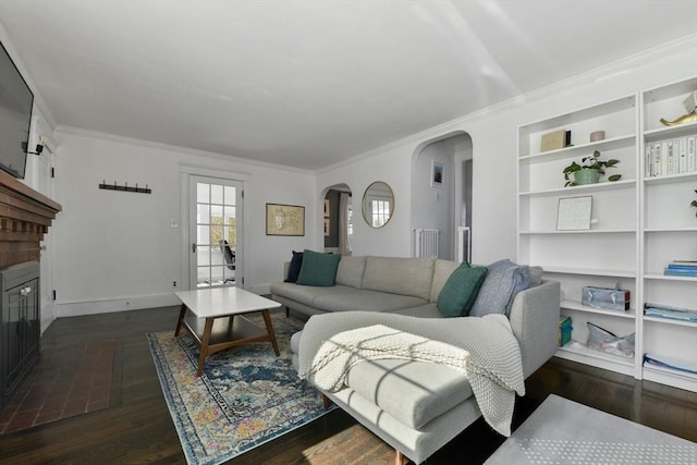 living room featuring dark wood-type flooring, a brick fireplace, and crown molding