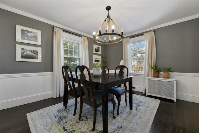 dining room featuring radiator, dark wood-type flooring, crown molding, and an inviting chandelier