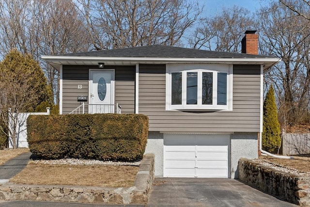 view of front of house featuring an attached garage, a chimney, concrete driveway, and roof with shingles