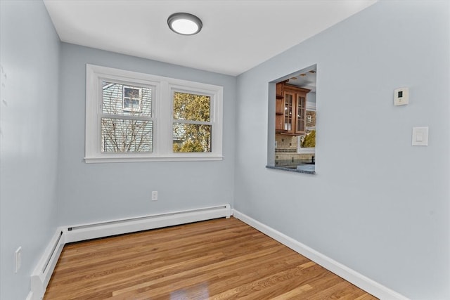 spare room with a baseboard radiator, baseboards, and wood finished floors