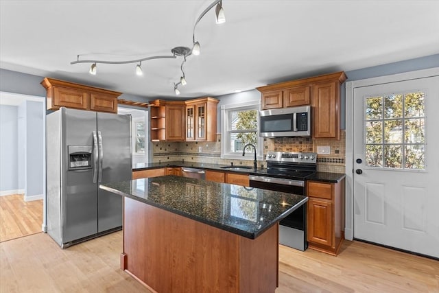 kitchen featuring light wood finished floors, appliances with stainless steel finishes, brown cabinets, and a sink