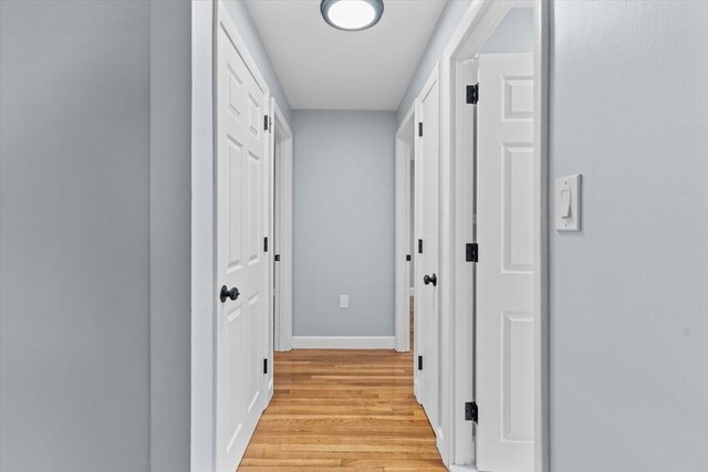 hallway featuring light wood finished floors and baseboards