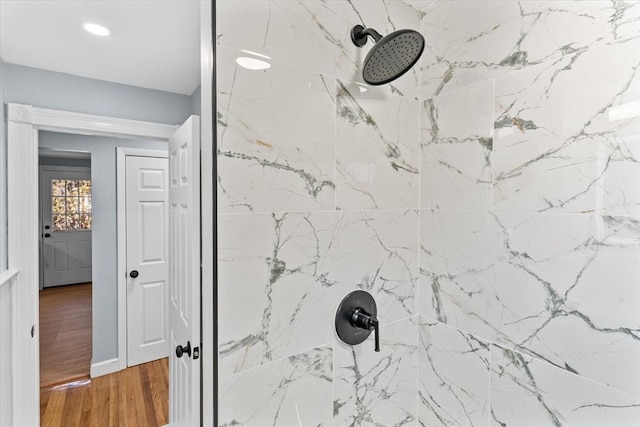 details with wood finished floors and a tile shower