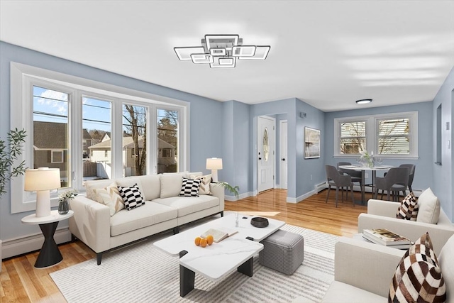 living room with a baseboard radiator, light wood-style flooring, and baseboards