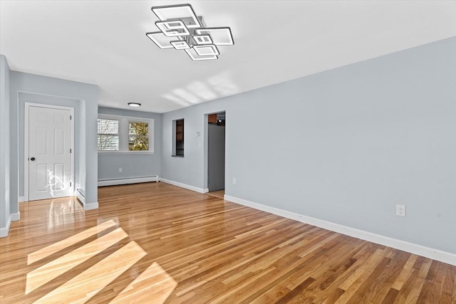 spare room featuring light wood finished floors, baseboards, and a baseboard heating unit