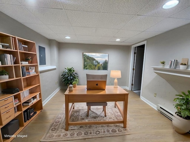 office featuring a paneled ceiling, baseboards, electric panel, and light wood finished floors