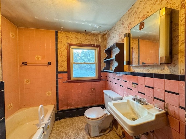 bathroom featuring a bathing tub, sink, tile walls, tile patterned flooring, and toilet