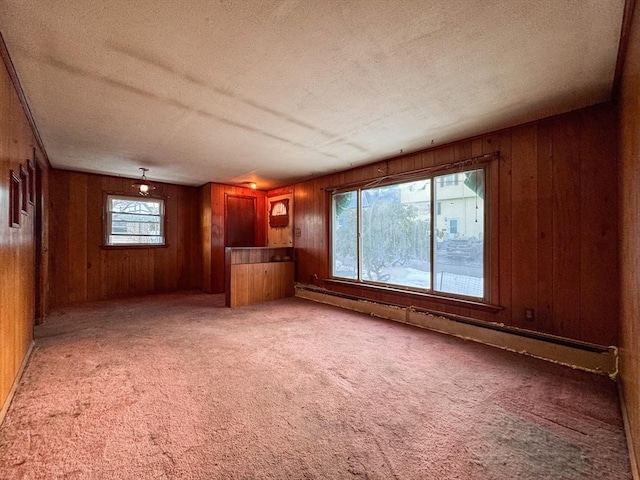 unfurnished living room with a baseboard radiator, carpet flooring, a textured ceiling, and wood walls