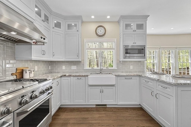 kitchen with exhaust hood, a sink, white cabinets, a peninsula, and stainless steel appliances