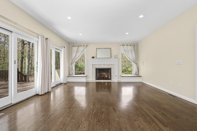 unfurnished living room featuring baseboards, visible vents, a healthy amount of sunlight, and wood finished floors