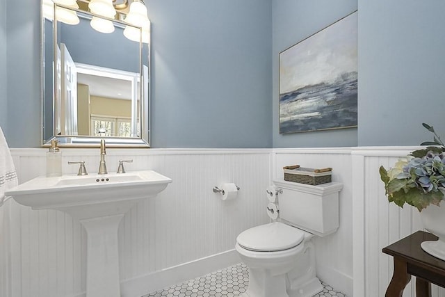 bathroom featuring a sink, a wainscoted wall, tile patterned floors, and toilet