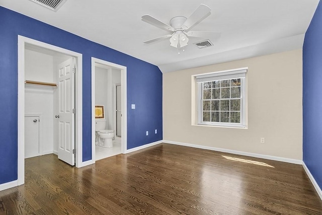 unfurnished bedroom with baseboards, ensuite bath, wood finished floors, and visible vents