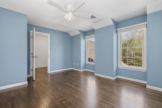 empty room featuring visible vents, a ceiling fan, wood finished floors, and a wealth of natural light