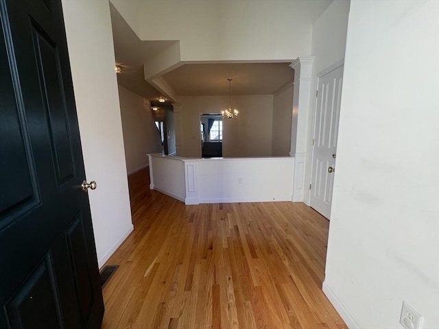 hall with light hardwood / wood-style flooring and an inviting chandelier