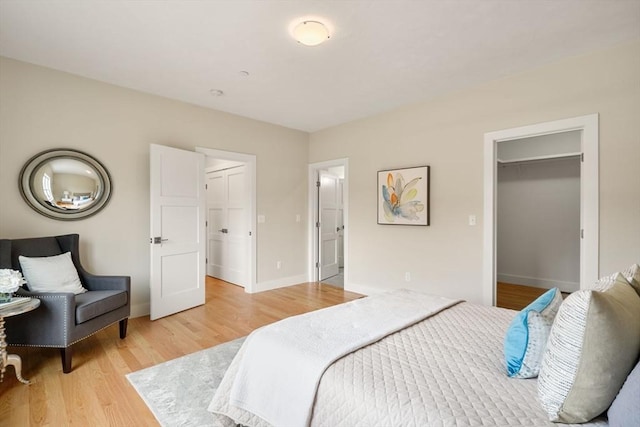 bedroom with light wood-type flooring, a closet, and a spacious closet