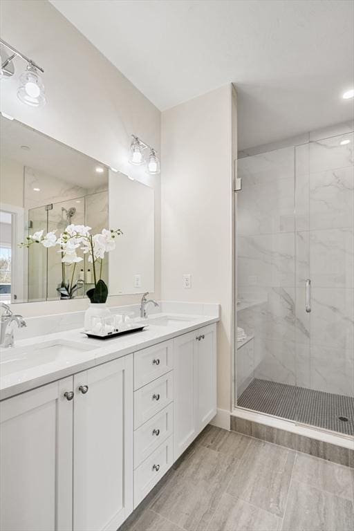 bathroom featuring a shower with shower door and vanity