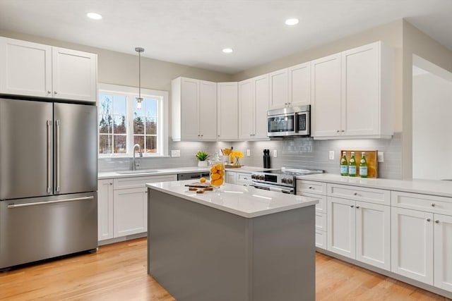 kitchen featuring white cabinets, decorative light fixtures, appliances with stainless steel finishes, and sink