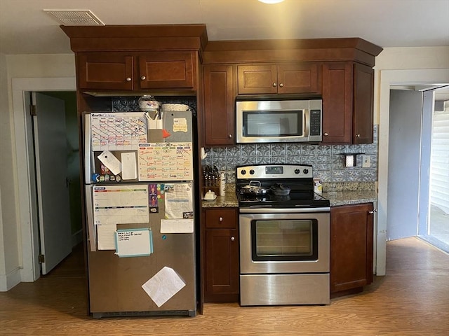 kitchen featuring stainless steel appliances, stone countertops, backsplash, and light hardwood / wood-style flooring