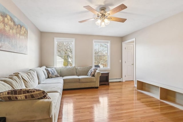 living room with light wood-type flooring, ceiling fan, and a baseboard heating unit