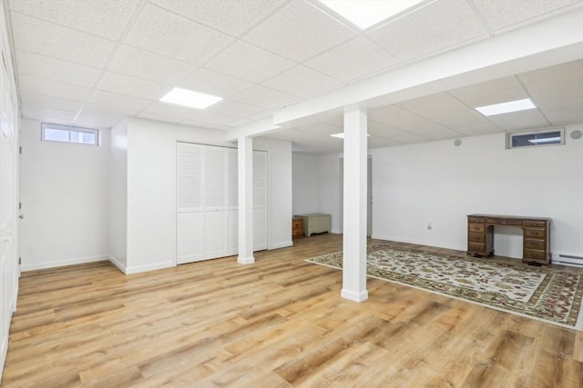 basement with a paneled ceiling, a baseboard radiator, and wood-type flooring