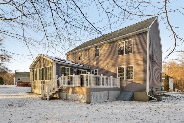 snow covered house with a deck and a sunroom