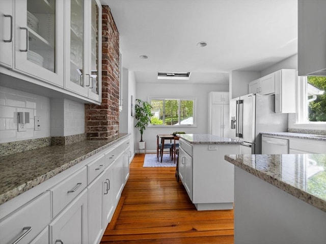 kitchen with white cabinets, light stone counters, a center island, tasteful backsplash, and dark wood-type flooring