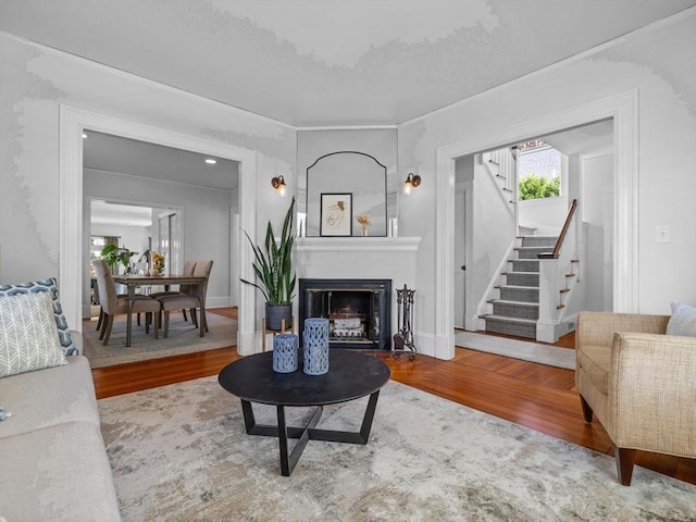 living area with stairs, baseboards, wood finished floors, and a fireplace
