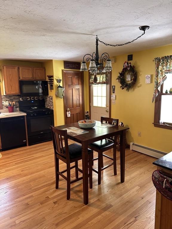 37 Teaberry Ln, Gardner, MA 01440 - dining space with a baseboard radiator, a chandelier, light wood-type flooring, a textured ceiling, and baseboards