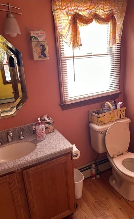 37 Teaberry Ln, Gardner, MA 01440 - bathroom featuring toilet, wood finished floors, vanity, baseboard heating, and plenty of natural light