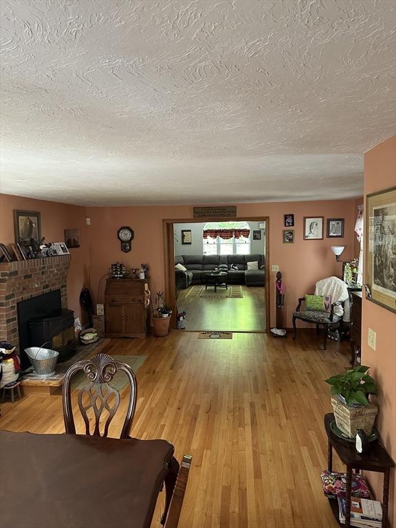 37 Teaberry Ln, Gardner, MA 01440 - dining space featuring a textured ceiling, wood finished floors, and a fireplace