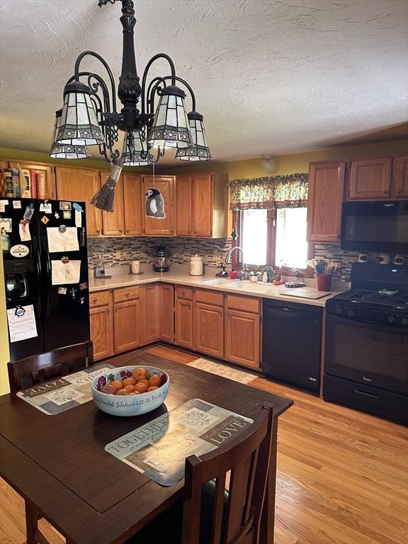 37 Teaberry Ln, Gardner, MA 01440 - kitchen with black appliances, light countertops, brown cabinets, decorative backsplash, and a chandelier