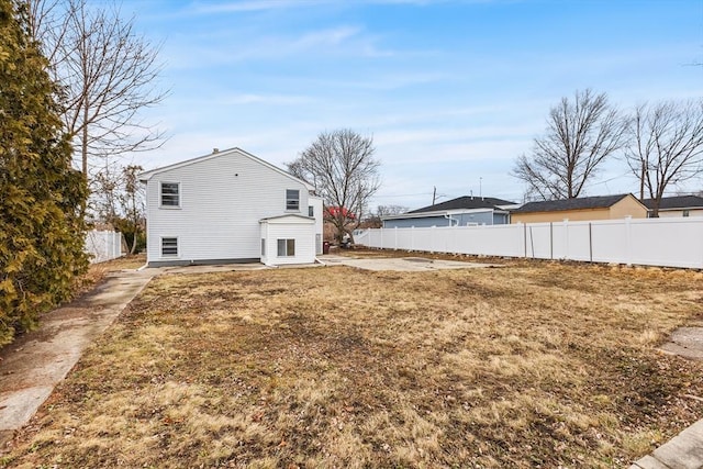 rear view of property with fence and a lawn