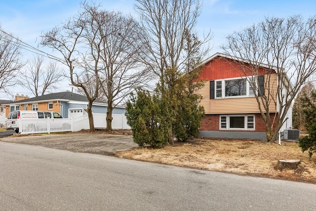 exterior space featuring central AC, brick siding, fence, and aphalt driveway