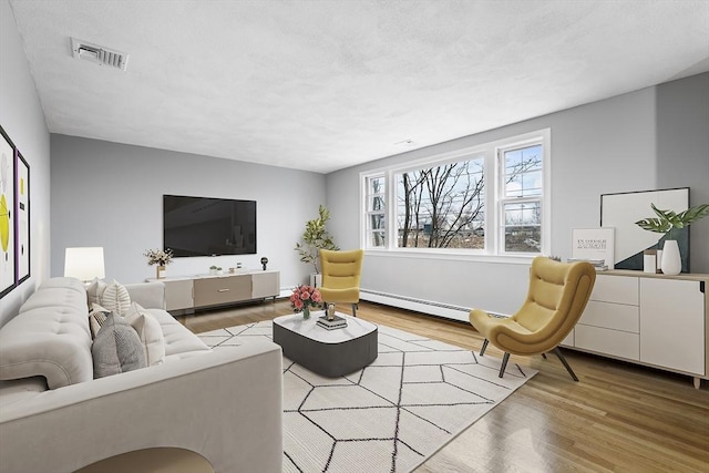 living area featuring a textured ceiling, baseboard heating, wood finished floors, and visible vents