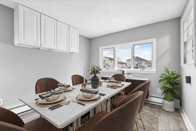 dining area featuring light wood finished floors, baseboards, and baseboard heating