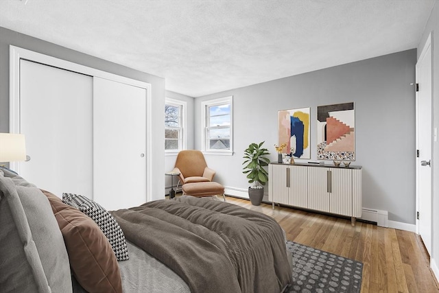 bedroom with a textured ceiling, a closet, wood finished floors, and baseboards