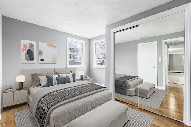 bedroom featuring a baseboard radiator, baseboards, visible vents, and wood finished floors