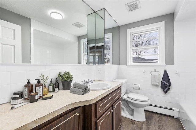 full bath featuring toilet, baseboard heating, visible vents, and tile walls