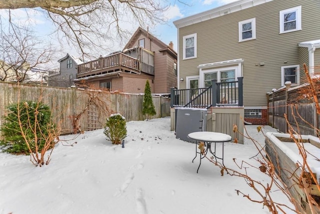 snow covered back of property with a deck