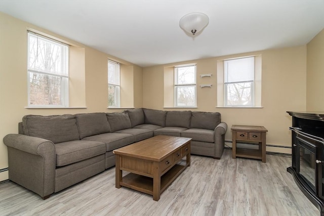 living room with a baseboard radiator, light hardwood / wood-style floors, and plenty of natural light