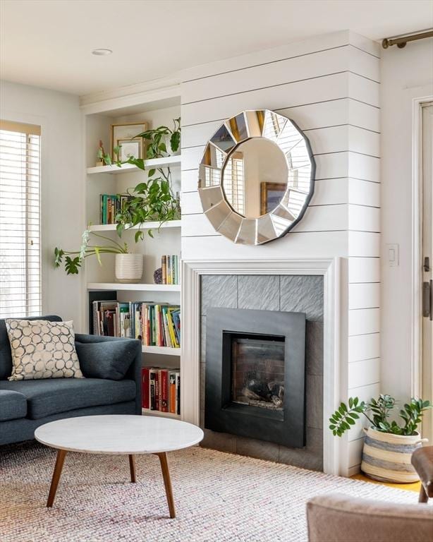 sitting room featuring a tiled fireplace and built in features