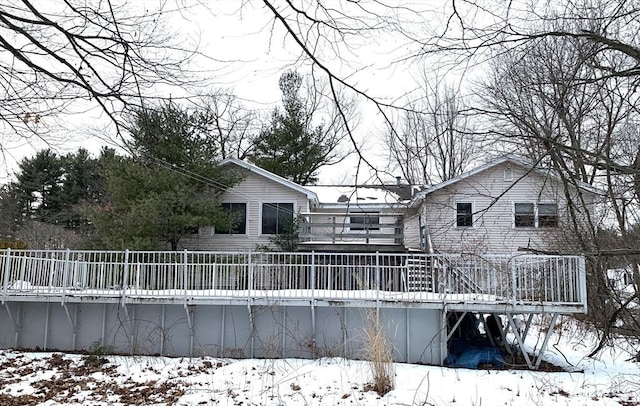 snow covered back of property with a deck