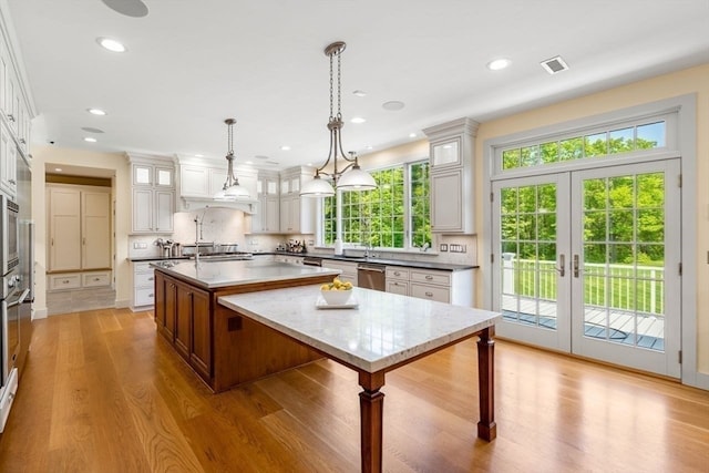 kitchen with a healthy amount of sunlight, light hardwood / wood-style floors, and a kitchen island with sink