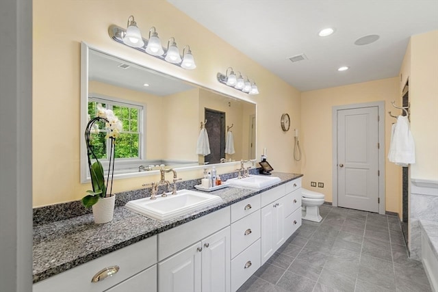 bathroom with dual vanity, tile flooring, a bath to relax in, and toilet